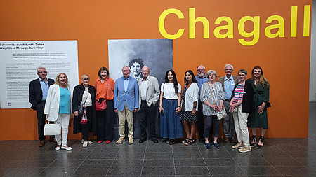 Teilnehmer der Ausstellung vor de Portrait von Marc Chagall